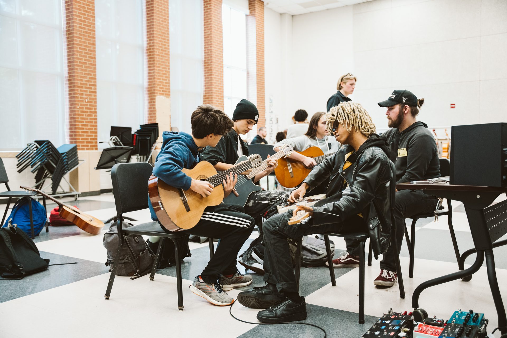 Students playing acoustic guitars in a classroom guitar session