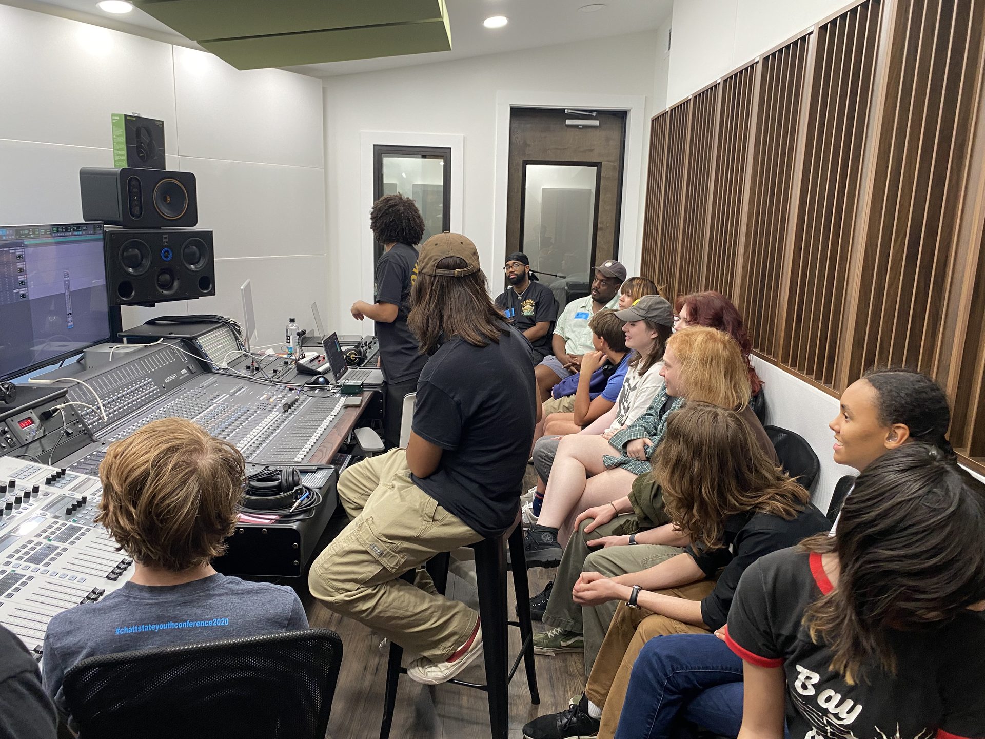 Students gathered around a mixing console in a recording studio